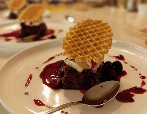 Chocolate dessert with cream, waffle cookie and berry coulis